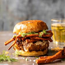 Crispy Quinoa Burgers Topped with Sweet Potato Fries and Beer Caramelized Onions.