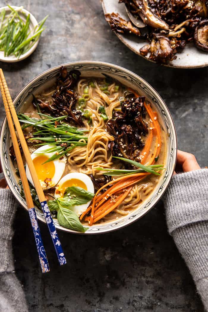overhead photo of 30 Minute Creamy Sesame Miso Ramen with Crispy Mushrooms with hands on soup bowl 