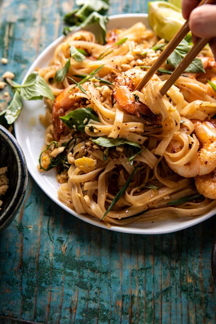 side angled photo of Better Than Takeout Garlic Butter Shrimp Pad Thai with chopsticks picking up the noodles