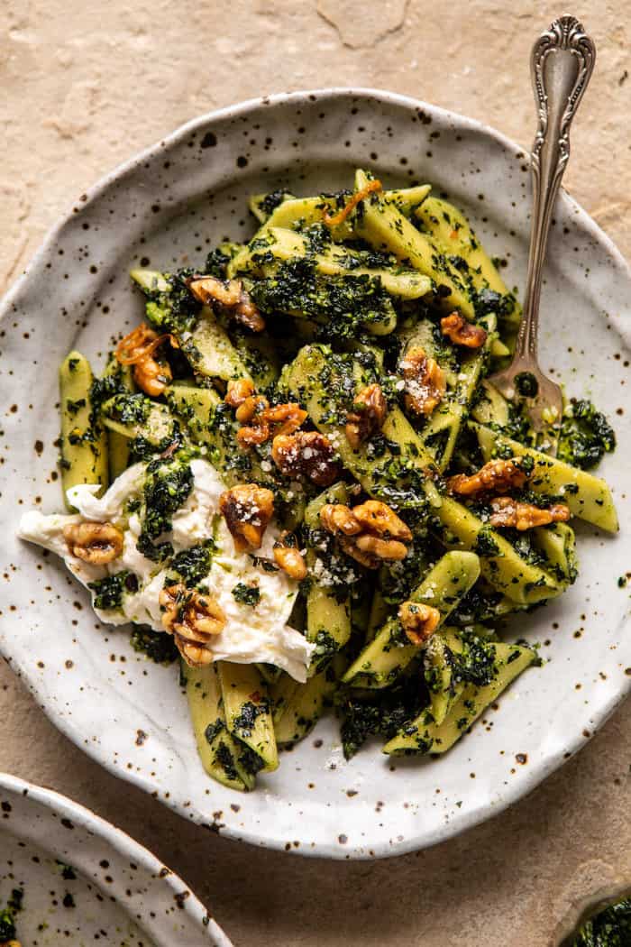 overhead photo of Herby Kale Pesto Pasta with Buttery Walnuts with fork in bowl 