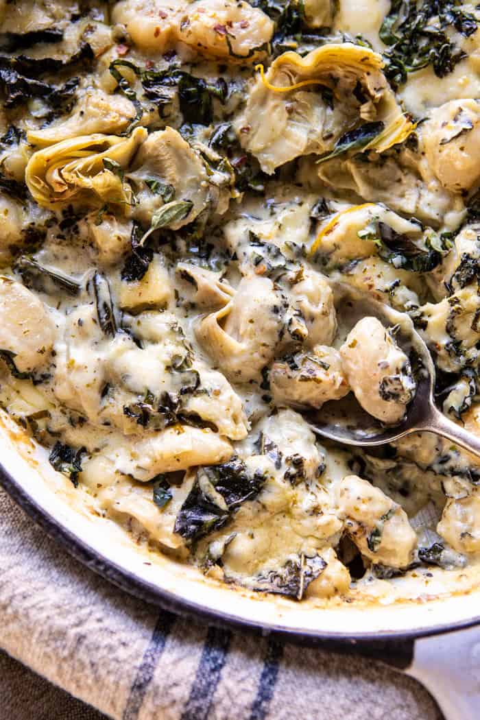 overhead close up photo of Skillet Baked Creamy Pesto Spinach and Artichoke Gnocchi 