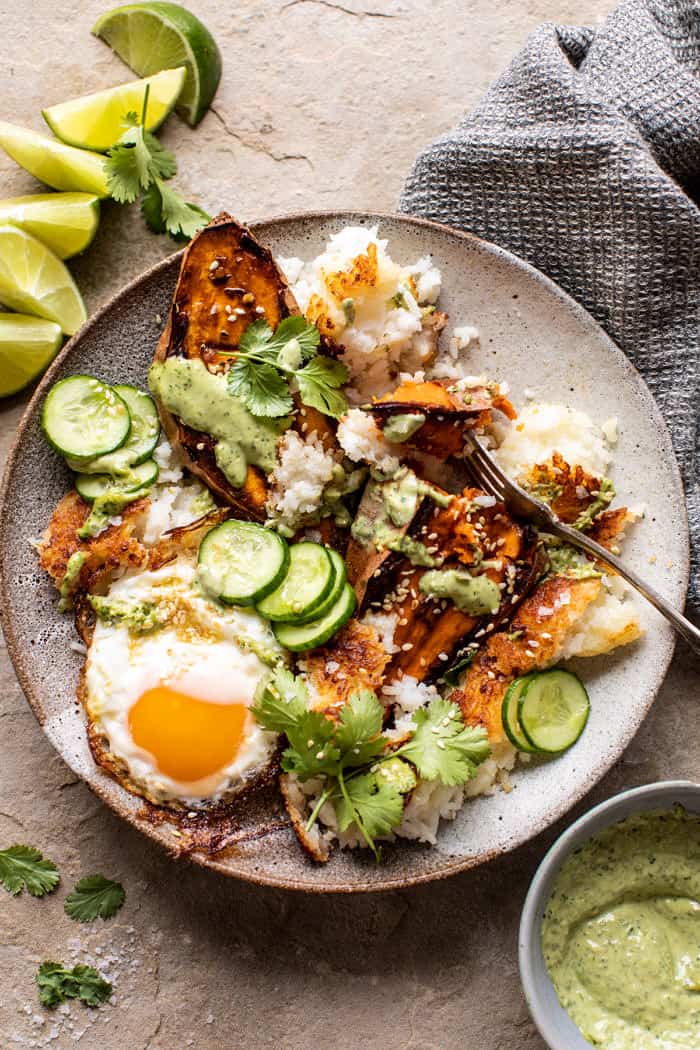 overhead photo of Crispy Rice Bowl with Browned Butter Sweet Potatoes and Herby Green Tahini and fork in bowl with sweet potatoes