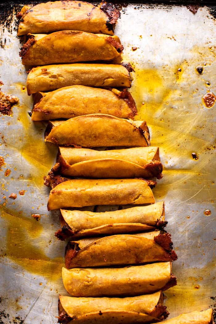 overhead photo of Crispy Chicken Tinga Taquitos after baking on baking sheet