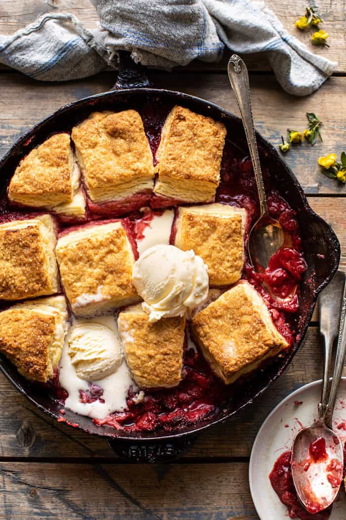 overhead photo of Skillet Strawberry Bourbon Cobbler with Layered Cream Cheese Biscuits with ice cream in skillet