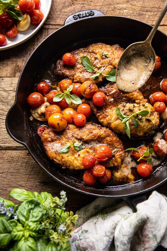 overhead photo of 20 Minute Florentine Butter Chicken with Burst Cherry Tomatoes in skillet with spoon pouring butter over chicken 