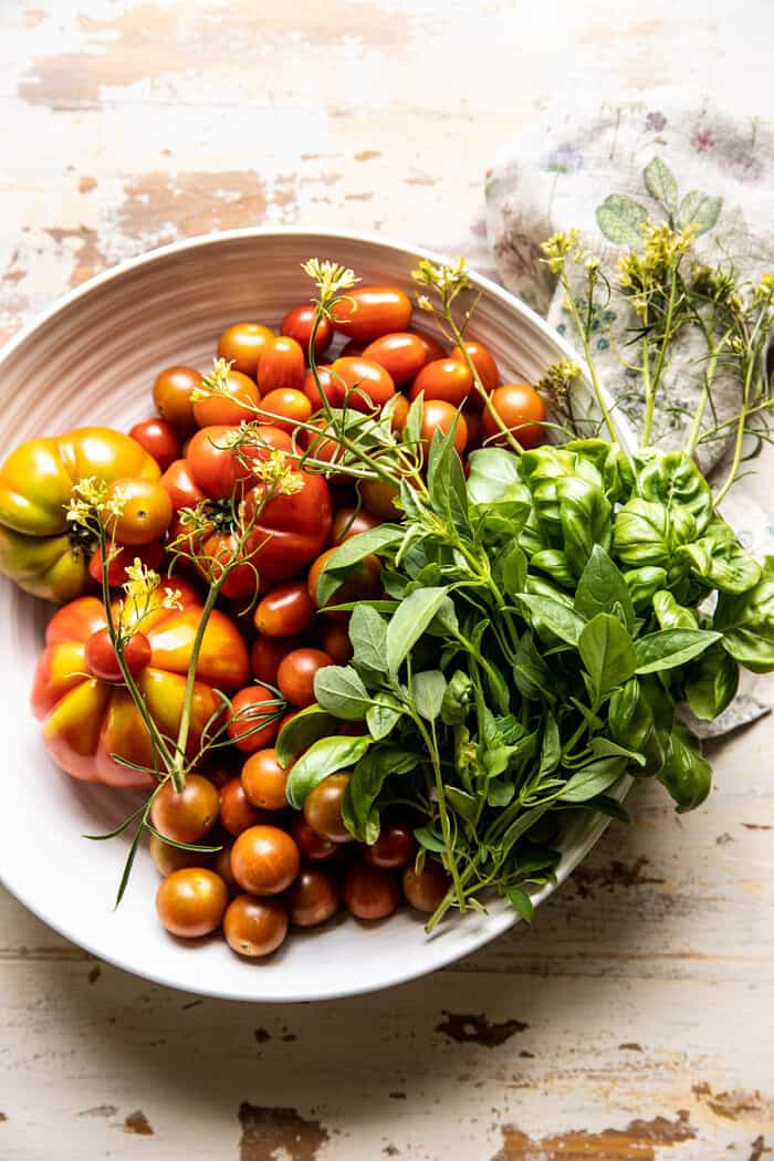 overhead photo of raw tomatoes and herbs in bowl 